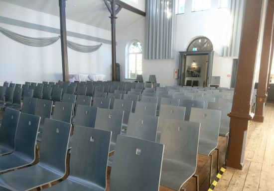 Ein Saal mit leeren Stühlen.